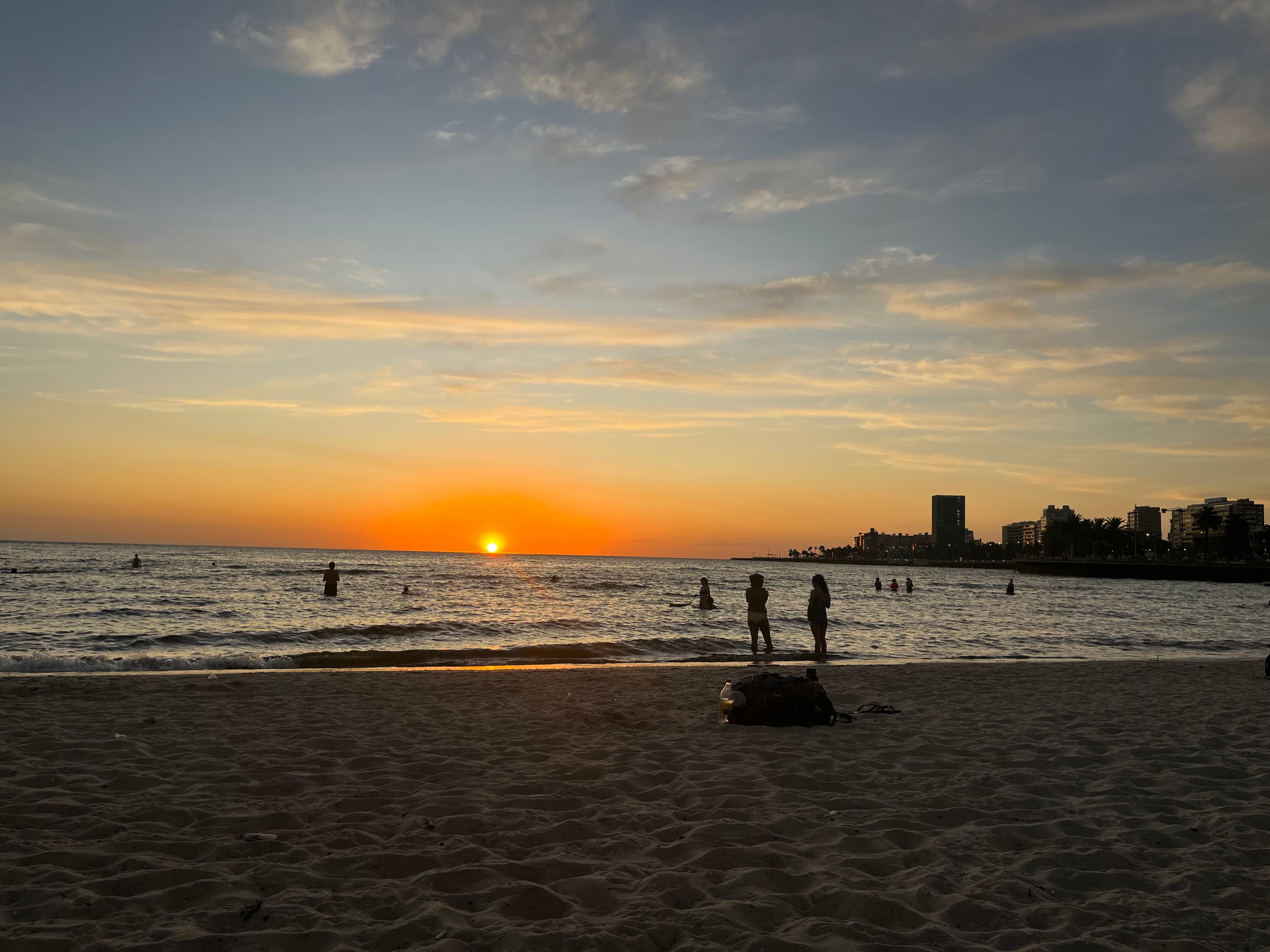 People gathered along a beach at sunset