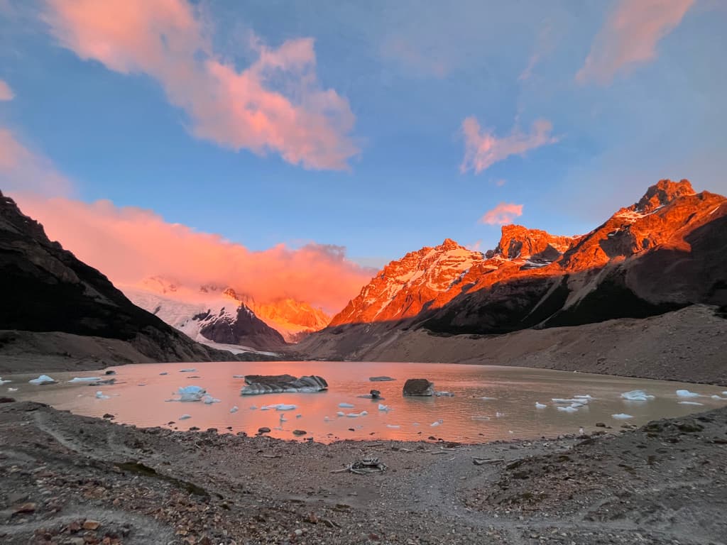 A glacial lake and surrounding mountains glowing orange in low evening light